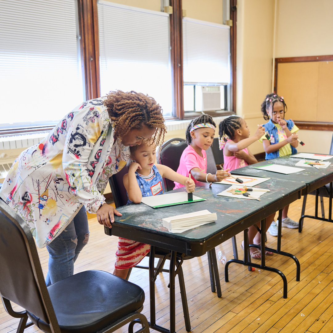 Nikki helping a child create art at a classroom table