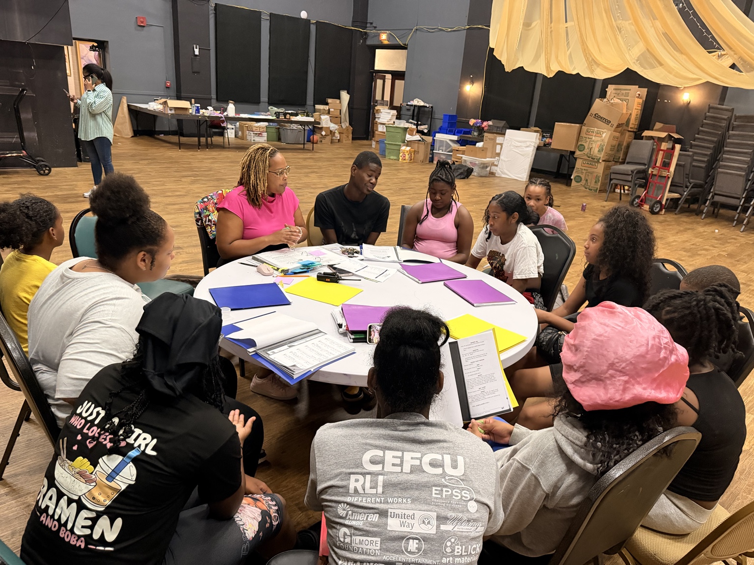 Nikki engaging with teens in a conversation around a table at ART INC
